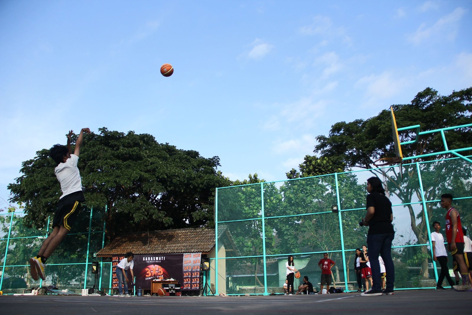Players enjoying a lively game of basketball on a sunny outdoor court.